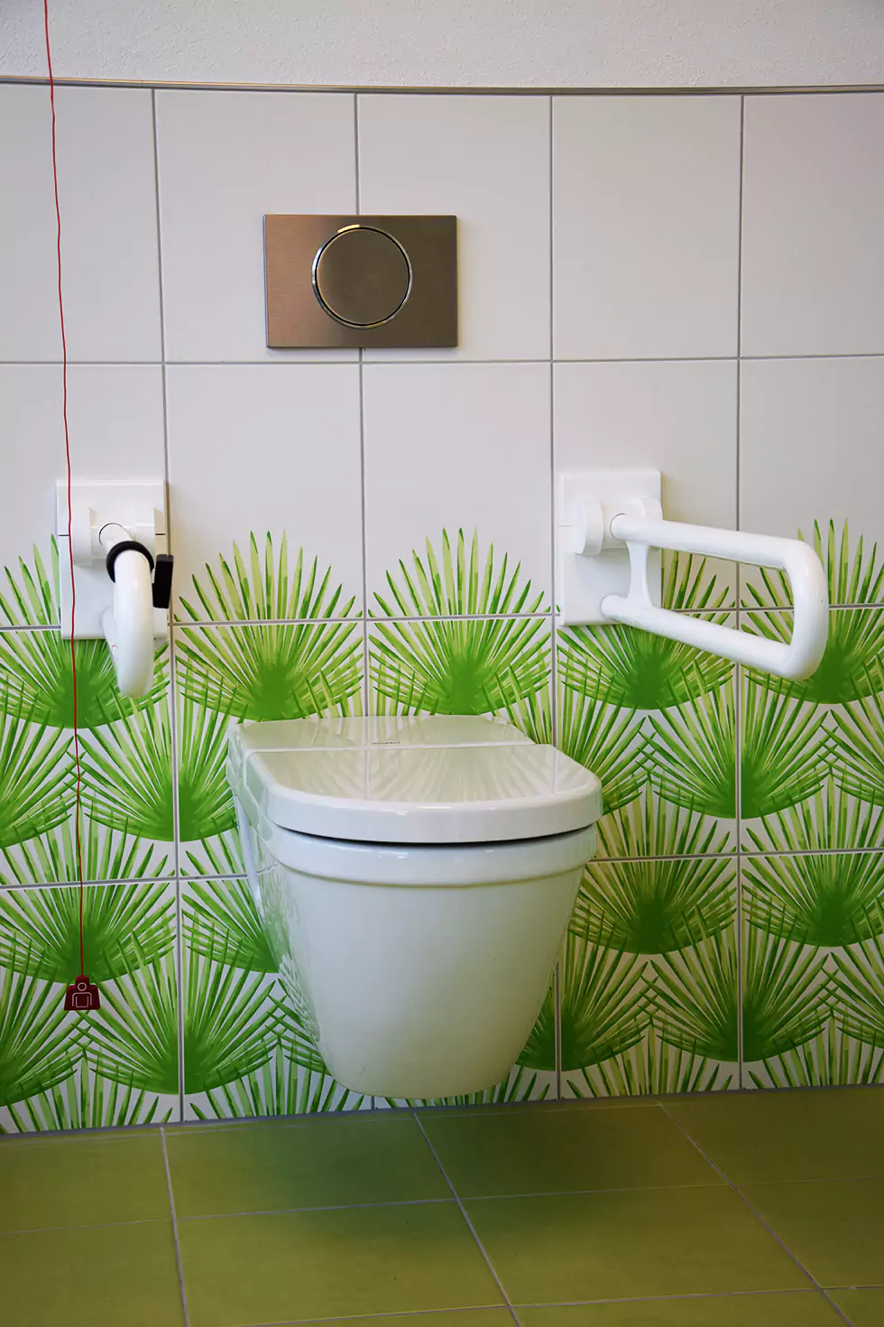 Toilette im Kindergarten mit Palmen-Fliesen an der Wand